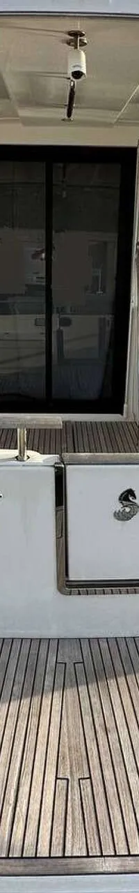 Een witte boot met een teakhouten zwemplateau en een schuifdeur naar de kajuit, liggend in een haven.