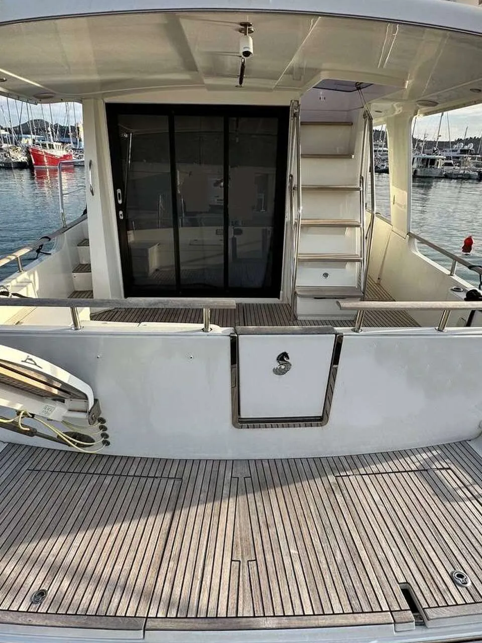 Een witte boot met een teakhouten zwemplateau en een schuifdeur naar de kajuit, liggend in een haven.