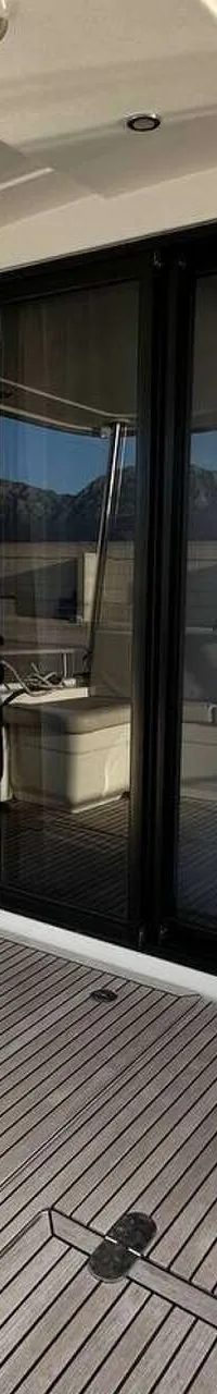 Een teakdek met een schuifdeur, een trap naar een hoger dek en een bankje aan de zijkant.