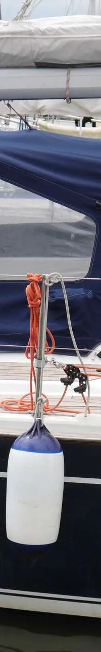Een zeilboot met een donkerblauwe romp en een witte opbouw, voorzien van een blauwe buiskap en twee fenders. — Dehler 39 SQ