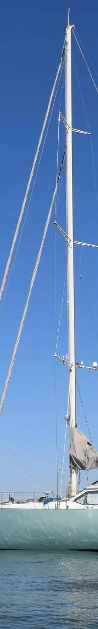 Een lichtgroene zeilboot genaamd "mahi mahi" ligt op het water met een opgerold zeil, mast en Nederlandse vlag. — CRN 63