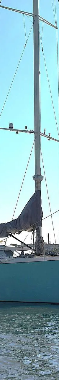 Een lichtblauwe zeilboot met de naam "mahi mahi" ligt op het water, met een opgerold zeil en een mast. — CRN 63