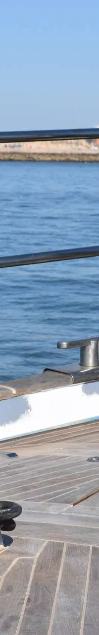 De foto toont het teakdek aan de boeg van een zeilboot met twee Reckmann rolreefsystemen, een ankerlier en bolders. — CRN 63
