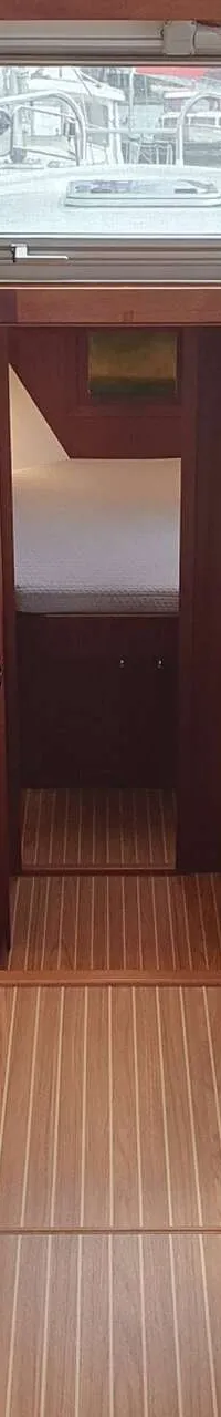 De foto toont het interieur van een boot met een stuurstand, kombuis, zithoek en doorgang naar een slaapcabine.