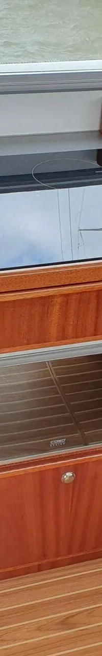 Een kombuis met een aanrecht, kookplaat, spoelbak, koffiezetapparaat, magnetron en houten kasten.