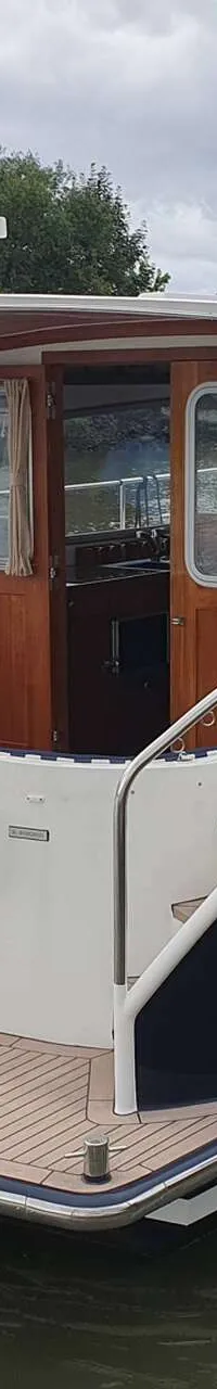 Een blauw-witte motorboot met de naam "GRETHE" ligt in het water, met een Duitse vlag aan de achtersteven.