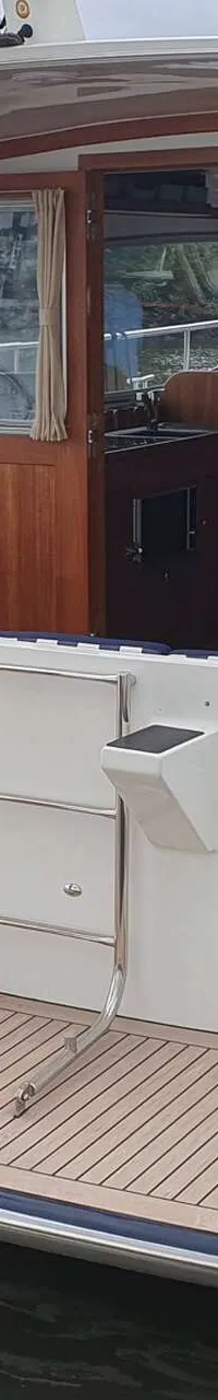 Een witte boot met een donkerblauwe romp en een Duitse vlag aan de achtersteven ligt in het water.
