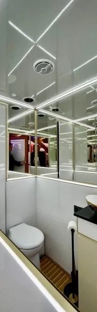 Een modern toilet met wastafel en spiegelwanden, verlicht met ledstrips.