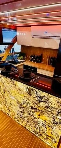 Een interieur van een boot met een keukenblok, een bank en houten vloer, verlicht met rode en paarse LED-strips.