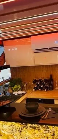 Een moderne keuken met een afzuigkap, airconditioning, koelkast, gootsteen, en een bar met twee gedekte plaatsen.