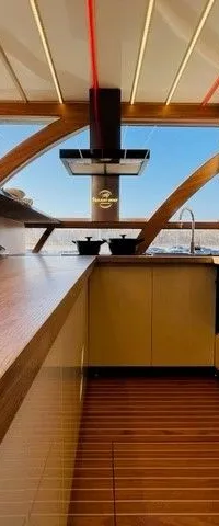 Een moderne kombuis met houten vloer, aanrecht en kasten, een gootsteen, kookplaat en afzuigkap.