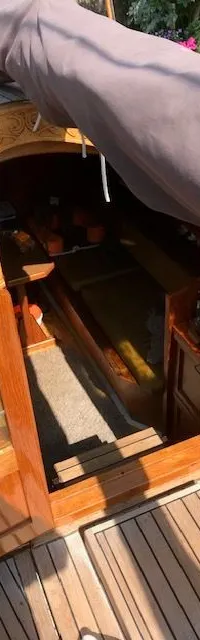 Een bovenaanzicht van de open kajuitingang van een boot met houten dek en deuren, en een bruine zeilhoes. — Gipon Grundel 800