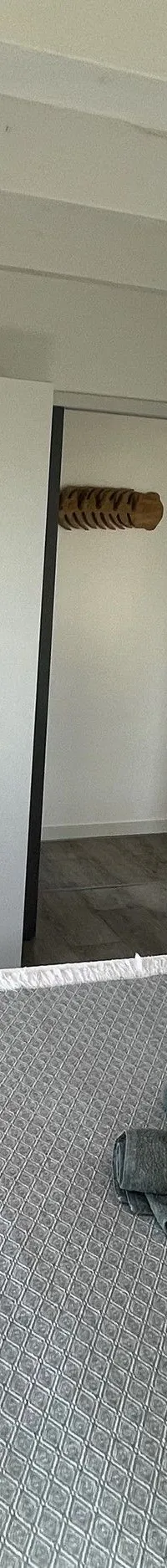 Een slaapkamer met een bed, witte kasten, een raam met uitzicht op water en een houten vlonder.