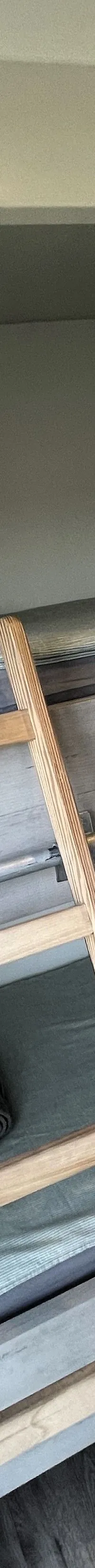 Een houten stapelbed met twee bedden, elk voorzien van een kussen, dekbed en opgerolde handdoek.