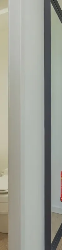 Een interieurfoto toont een toiletruimte met wastafel en een doorgang naar een slaapkamer, met een brandblusser in het…