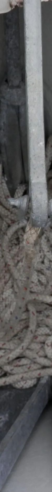 Een ankerkluis met een anker, een hoop wit touw en een metalen ring met touw aan de rechterzijde.