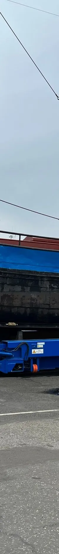 Een blauw-zwart schip met gele opbouw, WR53, staat op een blauwe trailer van Jachtcenter Elburg, terwijl een man de romp…