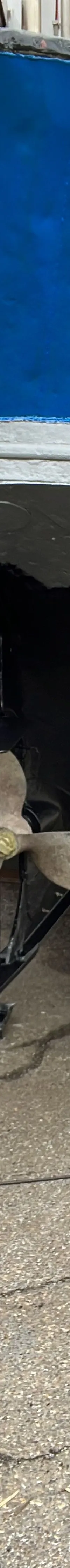 Een vrouw met een hoed en handschoenen schildert de onderkant van een blauwe boot die op bokken staat. — Garnalenkotter 15.50