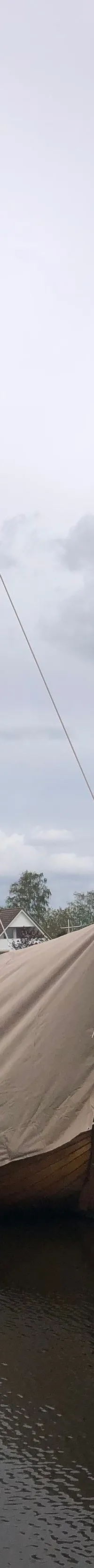 Een jachthaven met meerdere boten, waaronder een zeilboot met een beige afdekzeil en een motorboot met de naam "DEN HAAG".