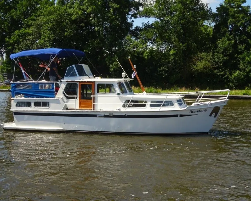 Een witte motorboot met blauwe bimini en de naam "Brandaris" op de boeg vaart op het water. — Pedro Kruiser 1000 AK