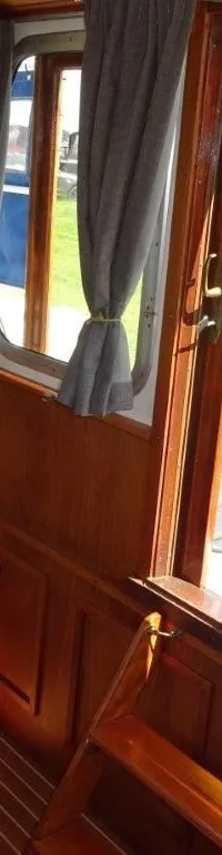 De foto toont het interieur van een boot met houten wanden en vloer, en een open deur naar buiten. — Pedro Kruiser 1000 AK