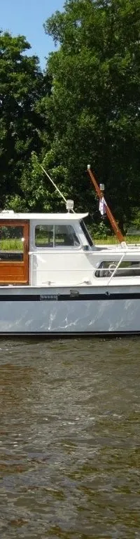 Een witte motorboot met blauwe kap en de naam "Brandaris" op de boeg vaart op het water. — Pedro Kruiser 1000 AK