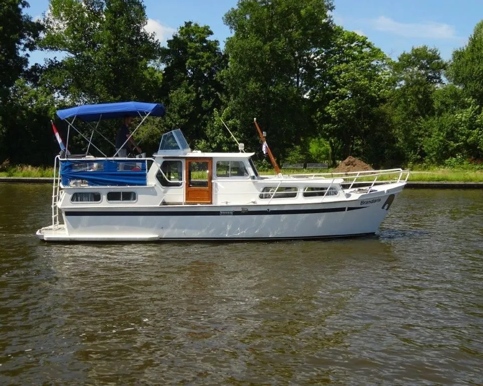 Een witte motorboot met blauwe kap en de naam "Brandaris" op de boeg vaart op het water. — Pedro Kruiser 1000 AK