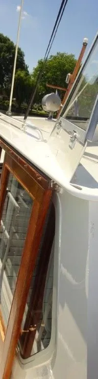 Een witte boot met houten ramen en een open dakraam ligt aangemeerd aan een houten steiger. — Pedro Kruiser 1000 AK