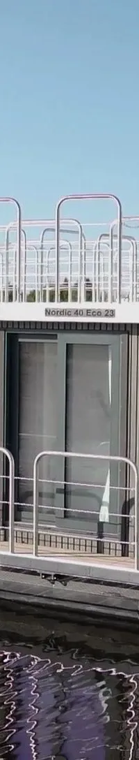 Een woonboot met een Yamaha buitenboordmotor, een trap naar het dak en de tekst "Nordic 40 Eco 23" op de zijkant.