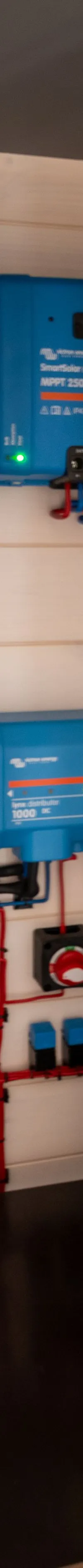 Een technische ruimte met diverse blauwe Victron Energy apparatuur, bedrading, schakelaars en een Bosch accu.
