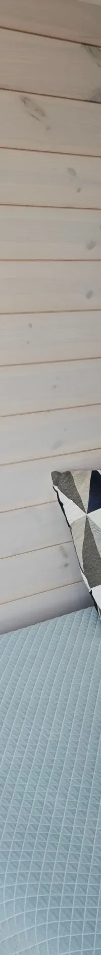 Een slaapkamer met een bed met blauw dekbed, twee kussens, een rond raam en houten wanden.