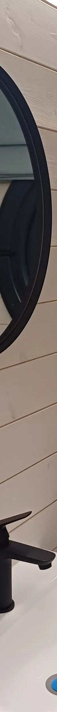 Een badkamer met een wastafel, spiegel, handdoekrek, patrijspoort en toilet.