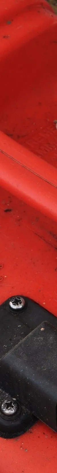 Een rode brandstoftank met een brandstofmeter en een zwarte aansluiting is zichtbaar, omringd door vuile schuimisolatie.