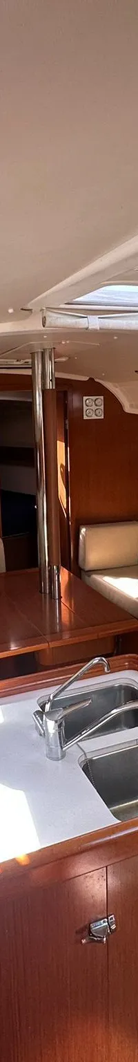 De foto toont het interieur van een boot met een kombuis, zithoek, houten meubels en ramen. — Beneteau Oceanis 37