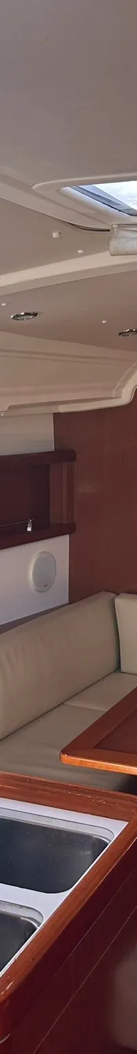 De foto toont het interieur van een boot met een kombuis, zithoek met tafel en een doorgang naar een hut.
