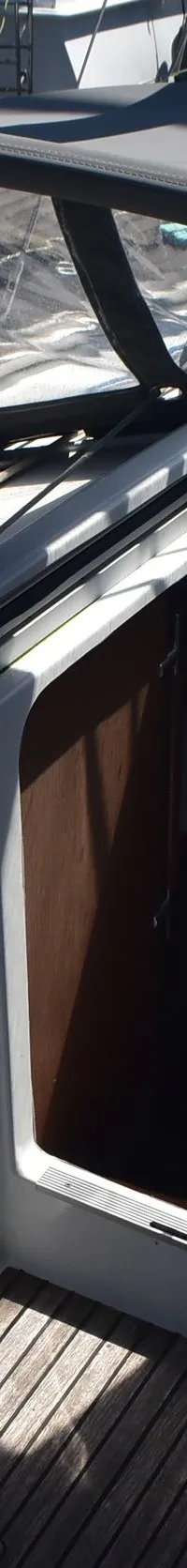 Een bovenaanzicht van een bootdek met een open kajuitingang, een donkergrijze buiskap en diverse touwen.