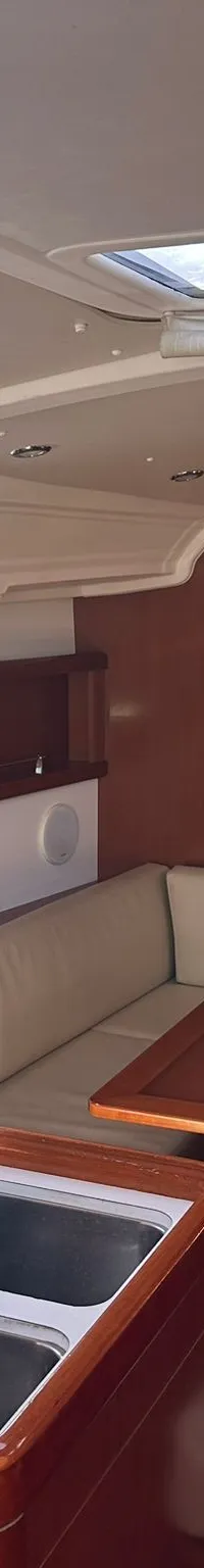 De foto toont het interieur van een boot met een kombuis, zithoek, tafel en een doorgang naar een slaapcabine.