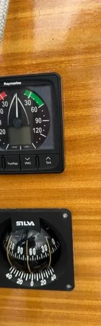 Op een houten oppervlak zijn een Raymarine windmeter en een Silva kompas gemonteerd, met touwen ernaast.