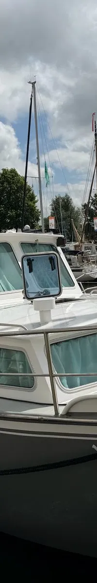 Een grijze motorboot met witte opbouw en de naam "Morgana" op de boeg ligt afgemeerd aan een betonnen kade. — Altena 10.50 AK