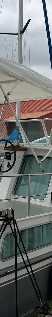 Een wit-grijze motorboot met een wit zonnedek en een stuurwiel is afgemeerd aan een betonnen kade. — Altena 10.50 AK