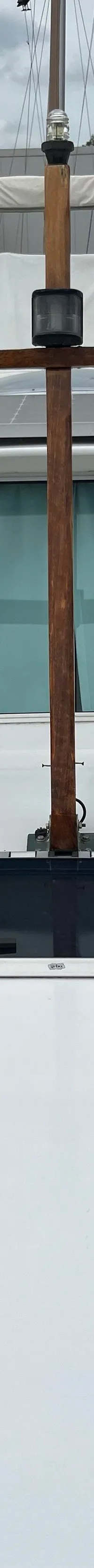 Een witte boot met drie ramen in de kajuit, zonnepanelen op het dak, een houten mast en een dubbele hoorn op het voordek.