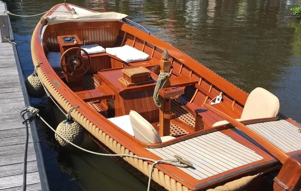 Een houten boot met een touw langs de rand, liggend aan een houten steiger. — De Jongvlet 6.20