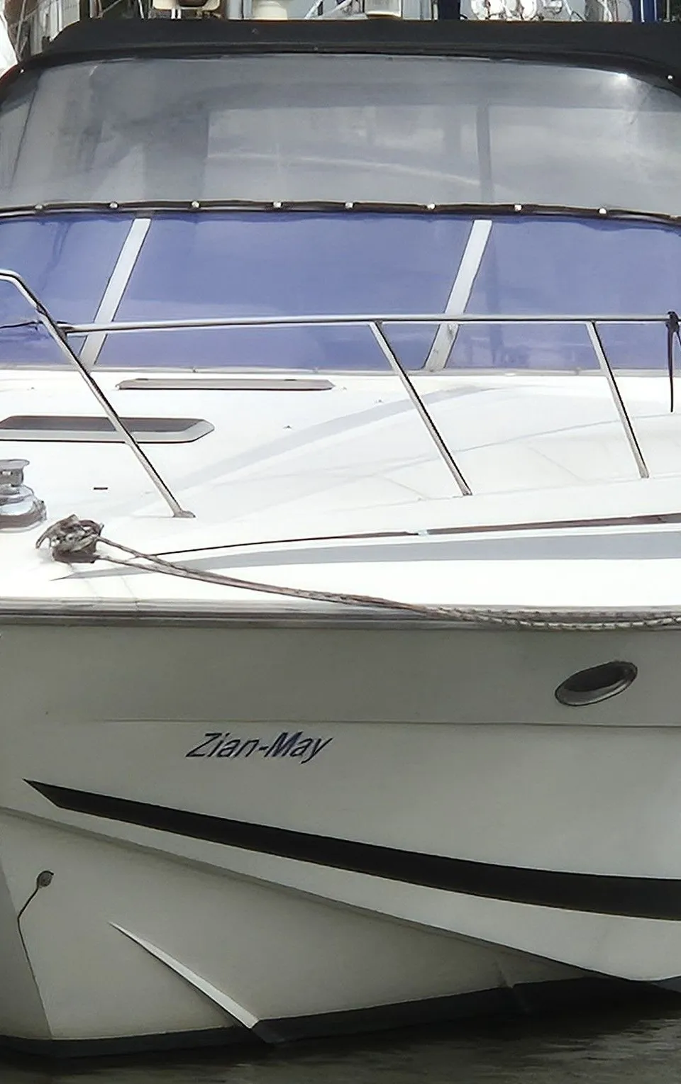 Een witte motorboot met de naam "Zian-May" ligt afgemeerd in een haven, omringd door andere boten. — Sunseeker 38 Martinique