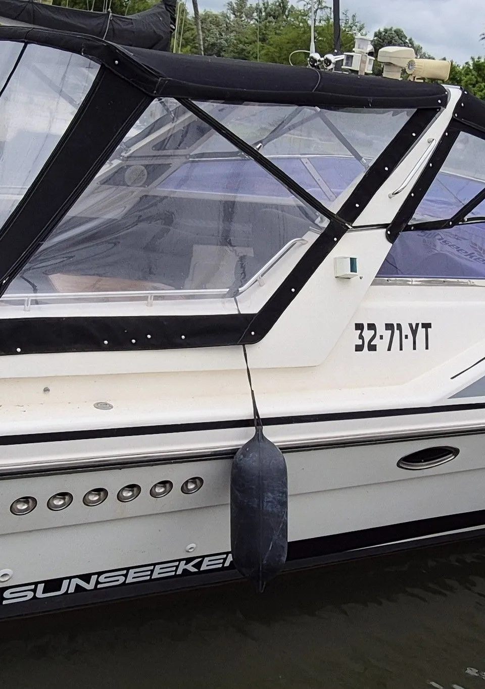Een witte motorboot met een zwarte kap en een Nederlands vlaggetje ligt aangemeerd in een haven. — Sunseeker 38 Martinique