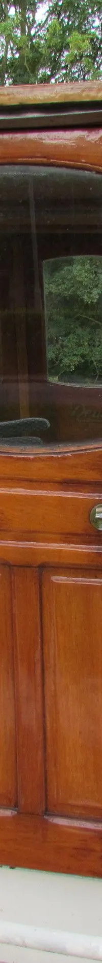 Een houten stuurhuis met ramen en een deur op een boot, met een reddingsboei en een hoorn zichtbaar.