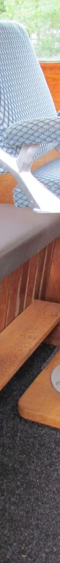 Een houten stuurhut met een grijze bank, een blauwe stoel, een houten stuurwiel en een "Deutz" logo op de deur.