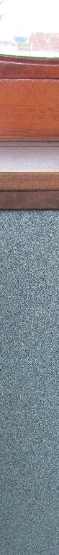 De foto toont een houten stuurwiel, een bedieningspaneel met meters en schakelaars, en twee blauwgrijze kastdeuren.