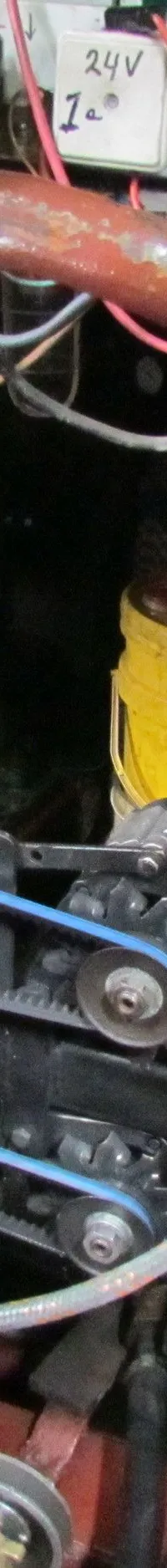 Een close-up van een motorruimte met een rood motorblok, een zilveren bedieningspaneel met een sleutel en knoppen, en…