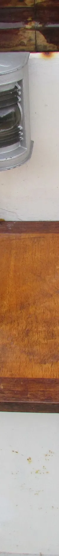 Een houten luik met een metalen lamp erboven, tegen een witte achtergrond met een bruine rand bovenaan.