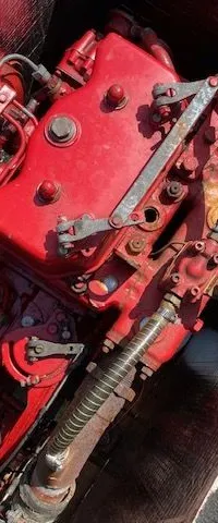 Een rode scheepsmotor is zichtbaar in een motorruimte met isolatiemateriaal en houten afwerking.